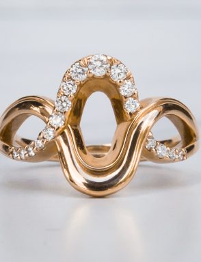 Rose Gold Saddle Ring with diamonds on a White Marble Surface